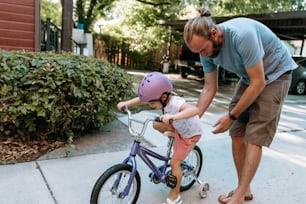 a man teaching a little girl how to ride a bike