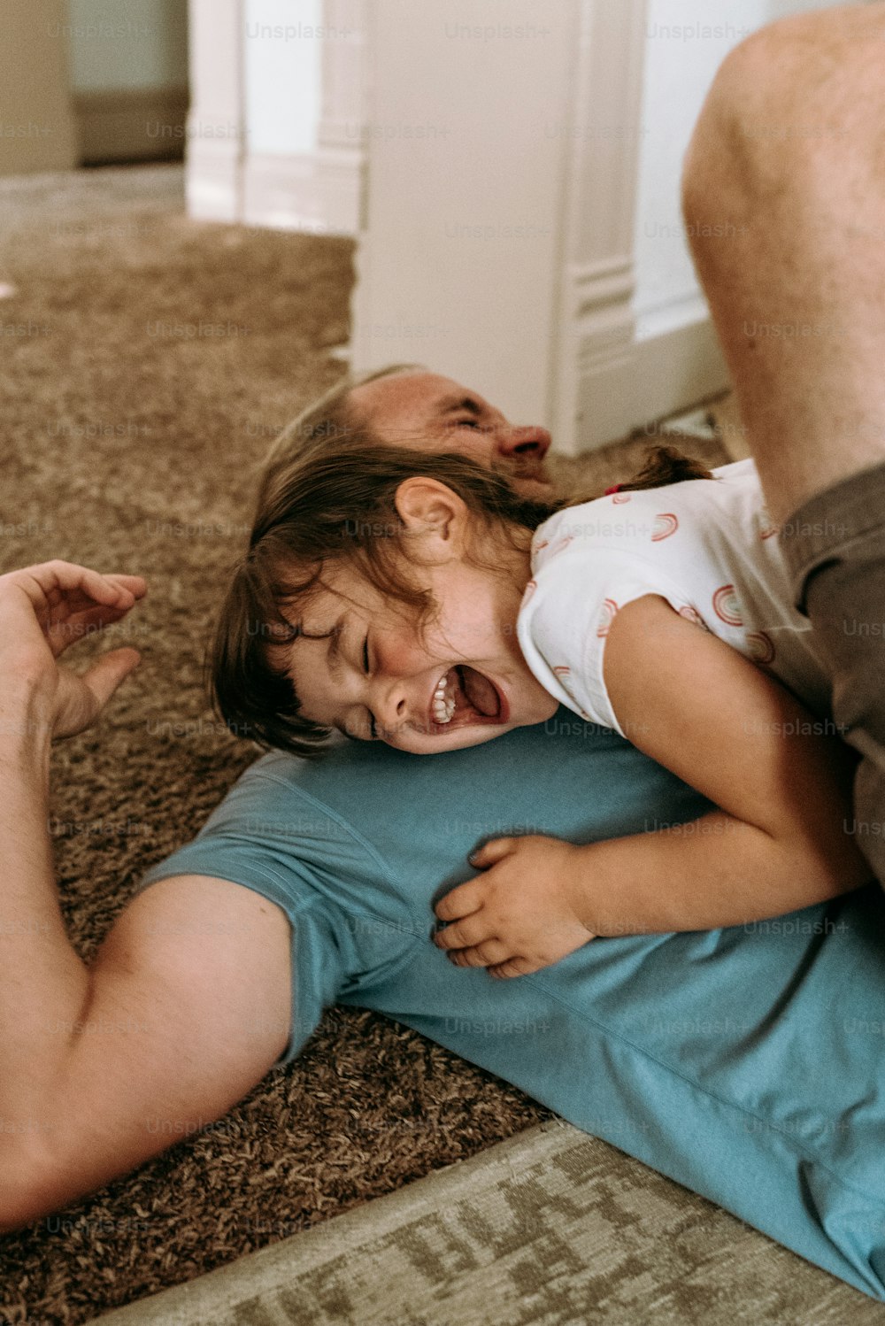 a man holding a little girl who is laying on the floor