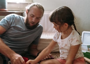 a man sitting next to a little girl on the floor