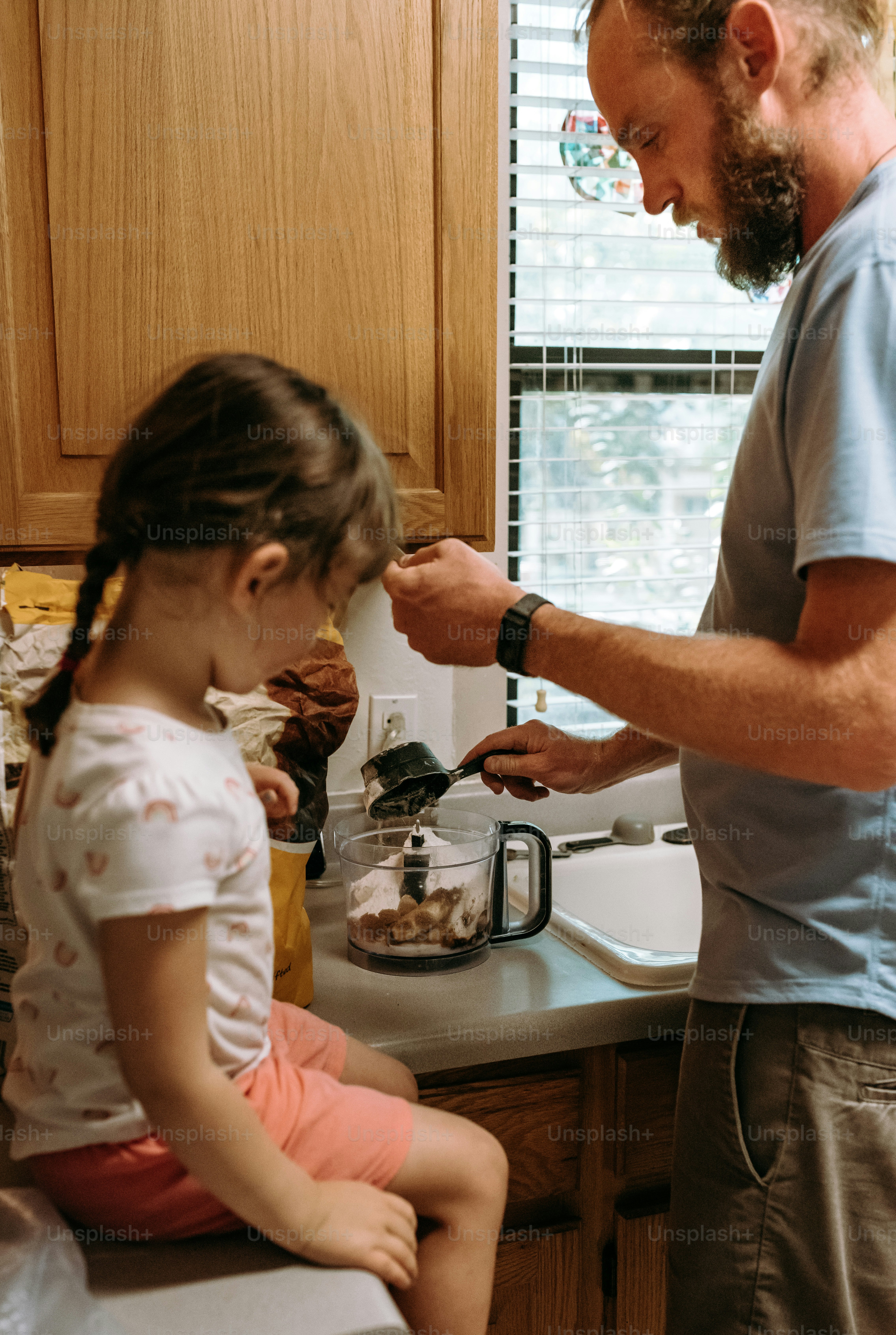 a man standing over a little girl in a kitchen