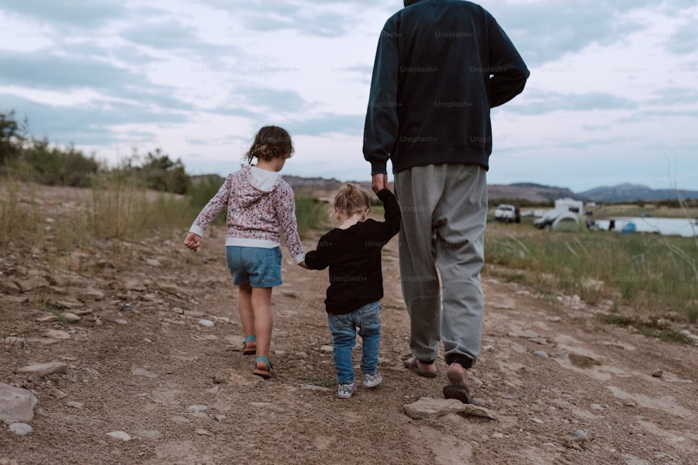 a man and a little girl walking down a dirt road