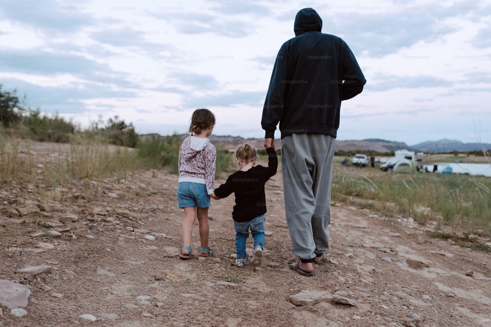 a man and two children walking down a dirt road