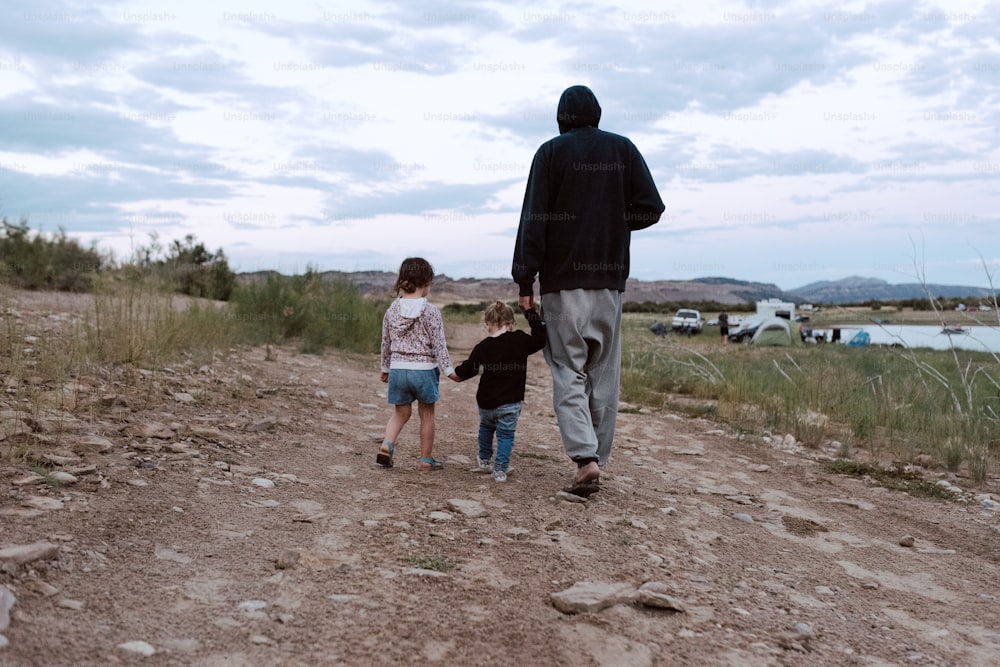 a man and two children walking down a dirt road