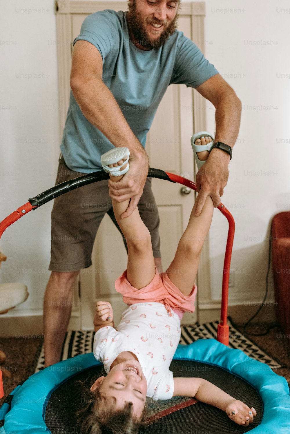 Ein Mann, der einem kleinen Mädchen auf einem Trampolin hilft