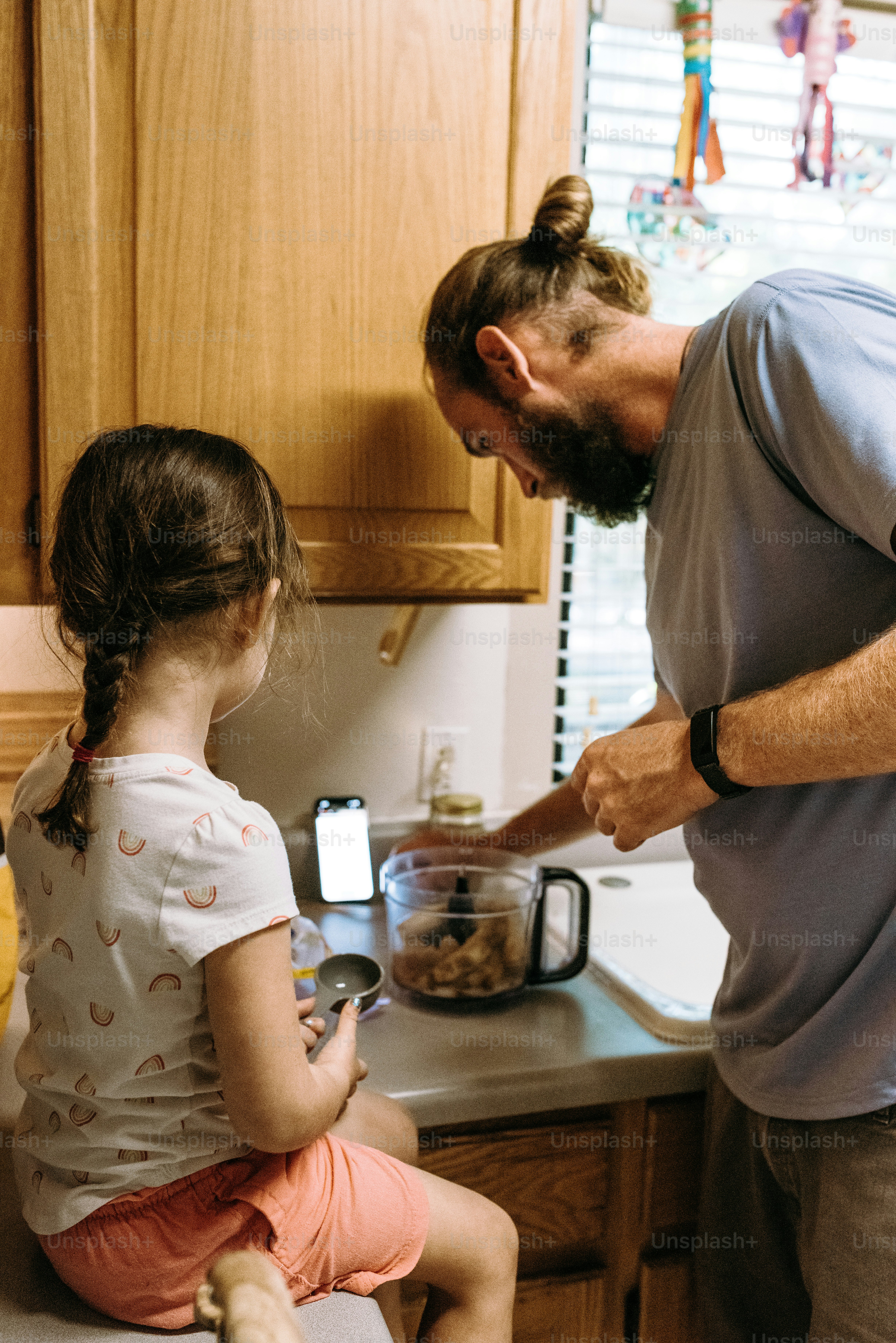 a man standing over a little girl in a kitchen