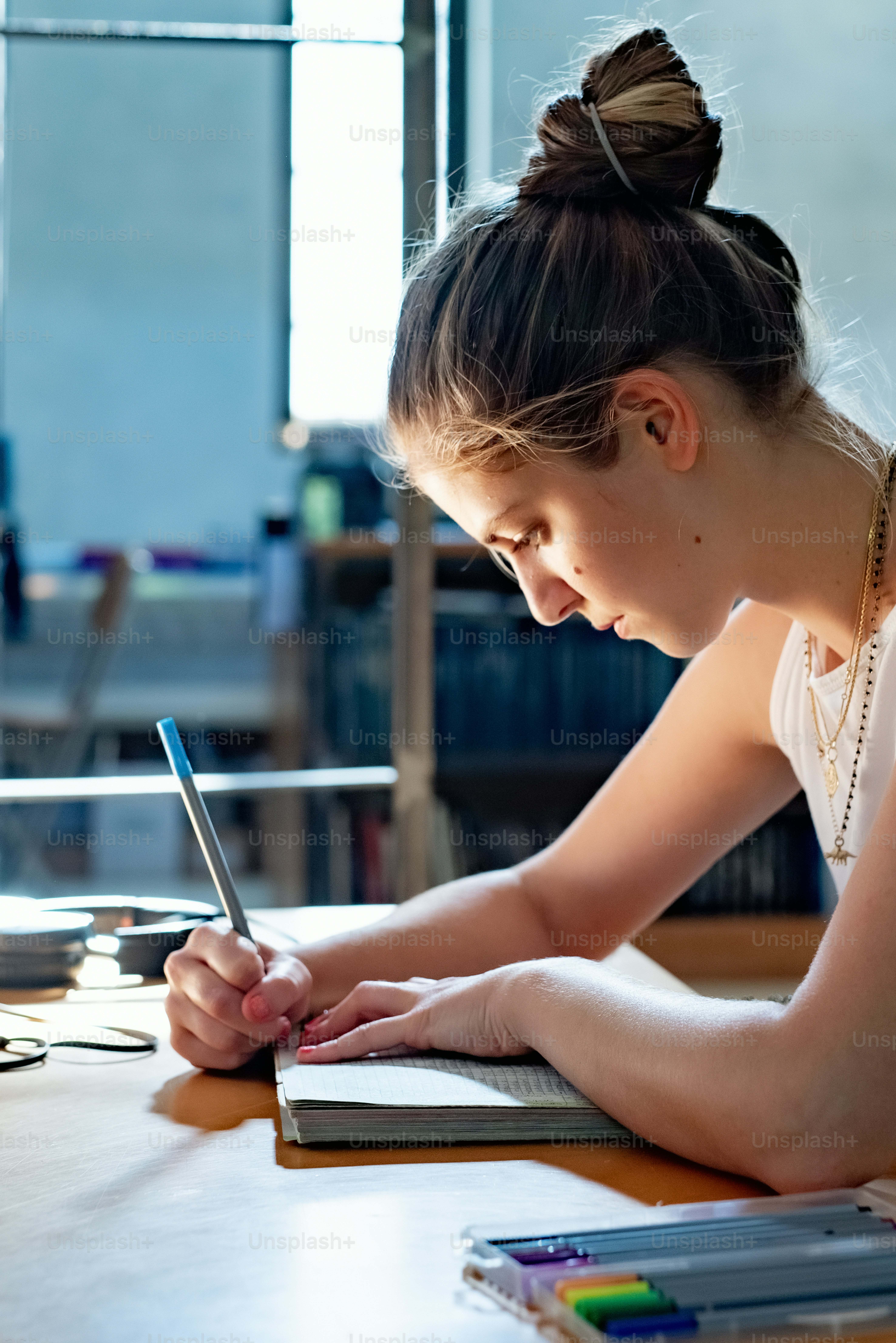 a woman sitting at a table writing on a notebook