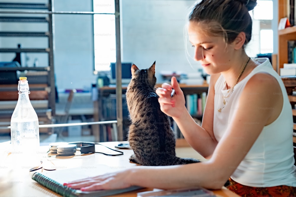 a woman sitting at a table with a cat