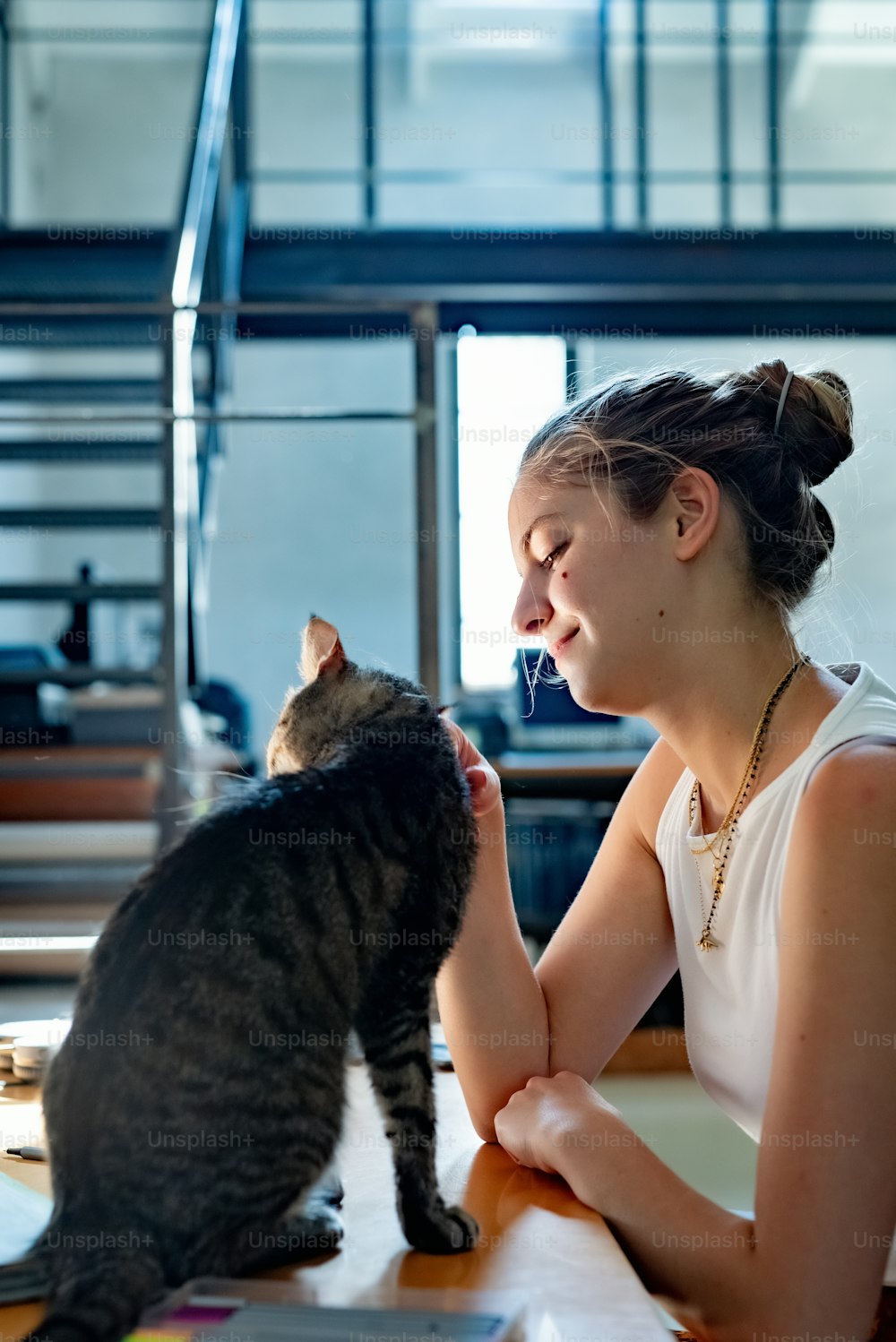 une femme assise à une table caressant un chat