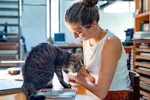 a woman sitting at a desk with a cat