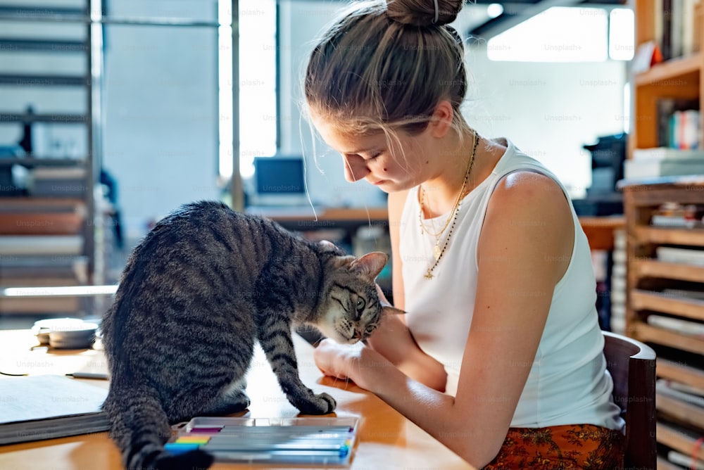 Eine Frau, die mit einer Katze an einem Schreibtisch sitzt