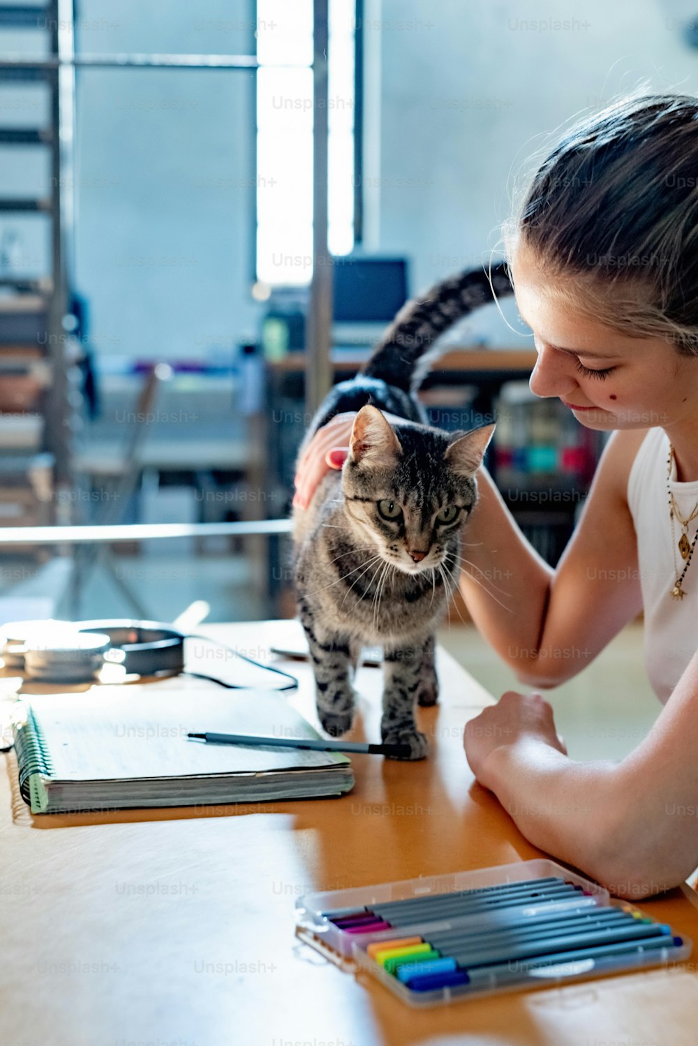a woman sitting at a table petting a cat
