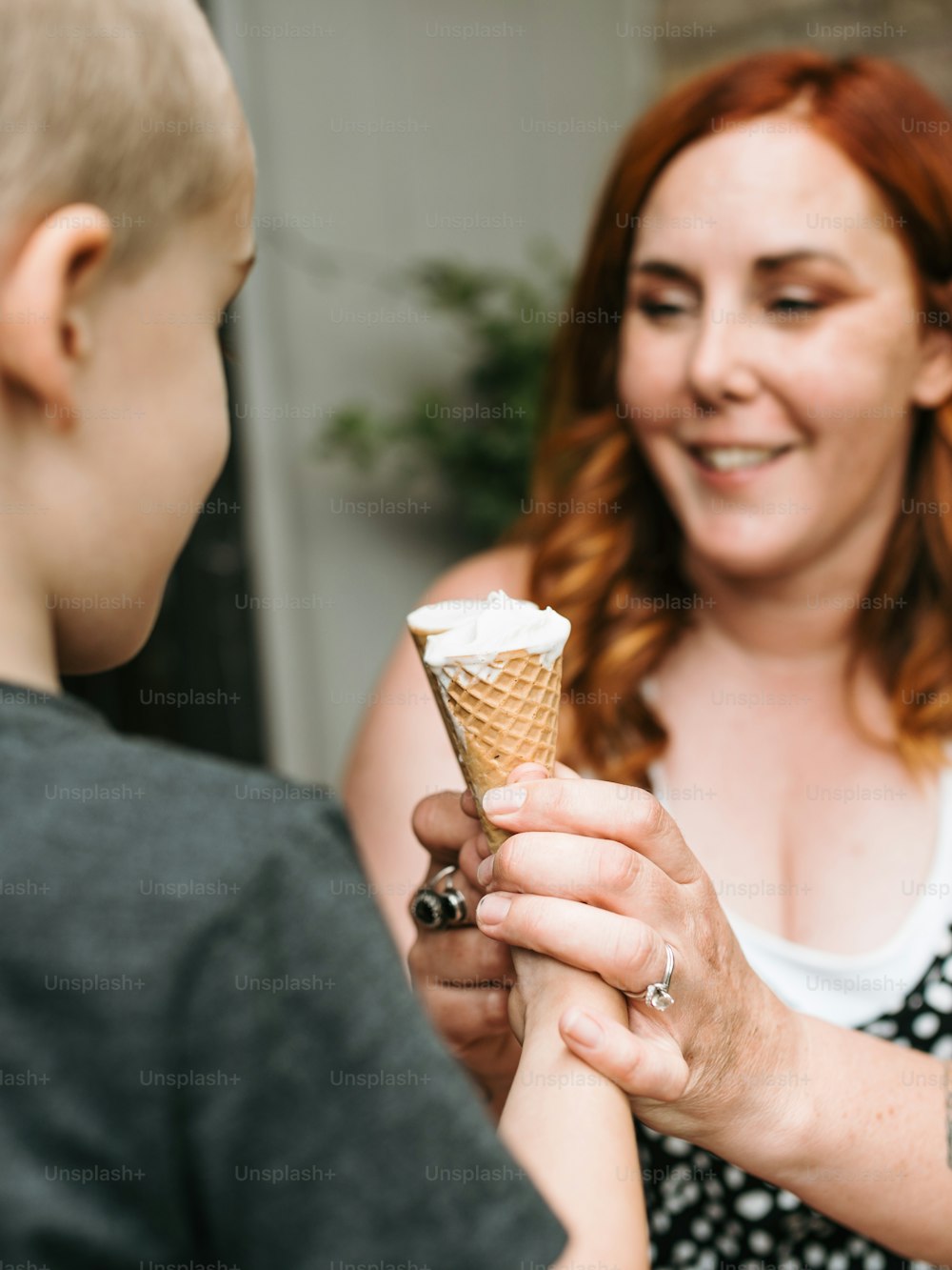 uma mulher segurando uma casquinha de sorvete para um menino