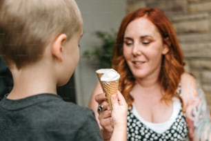 Une femme tenant un cornet de crème glacée à un garçon