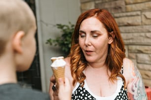 uma mulher segurando uma casquinha de sorvete na mão