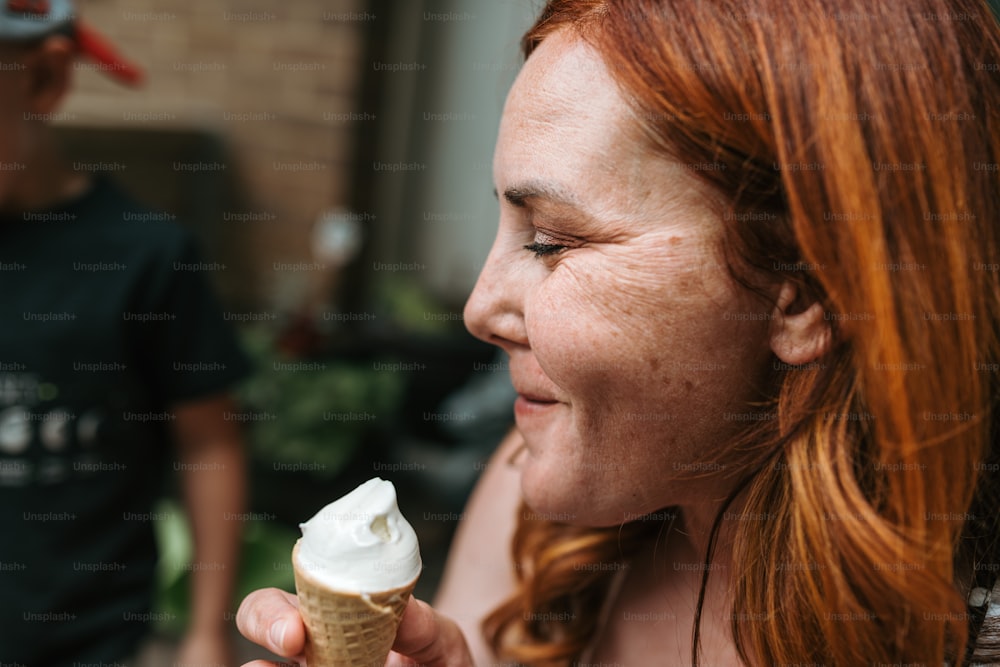 uma mulher com cabelo ruivo comendo uma casquinha de sorvete