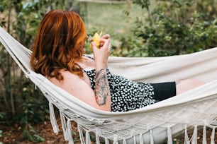 a woman laying in a hammock eating a piece of fruit