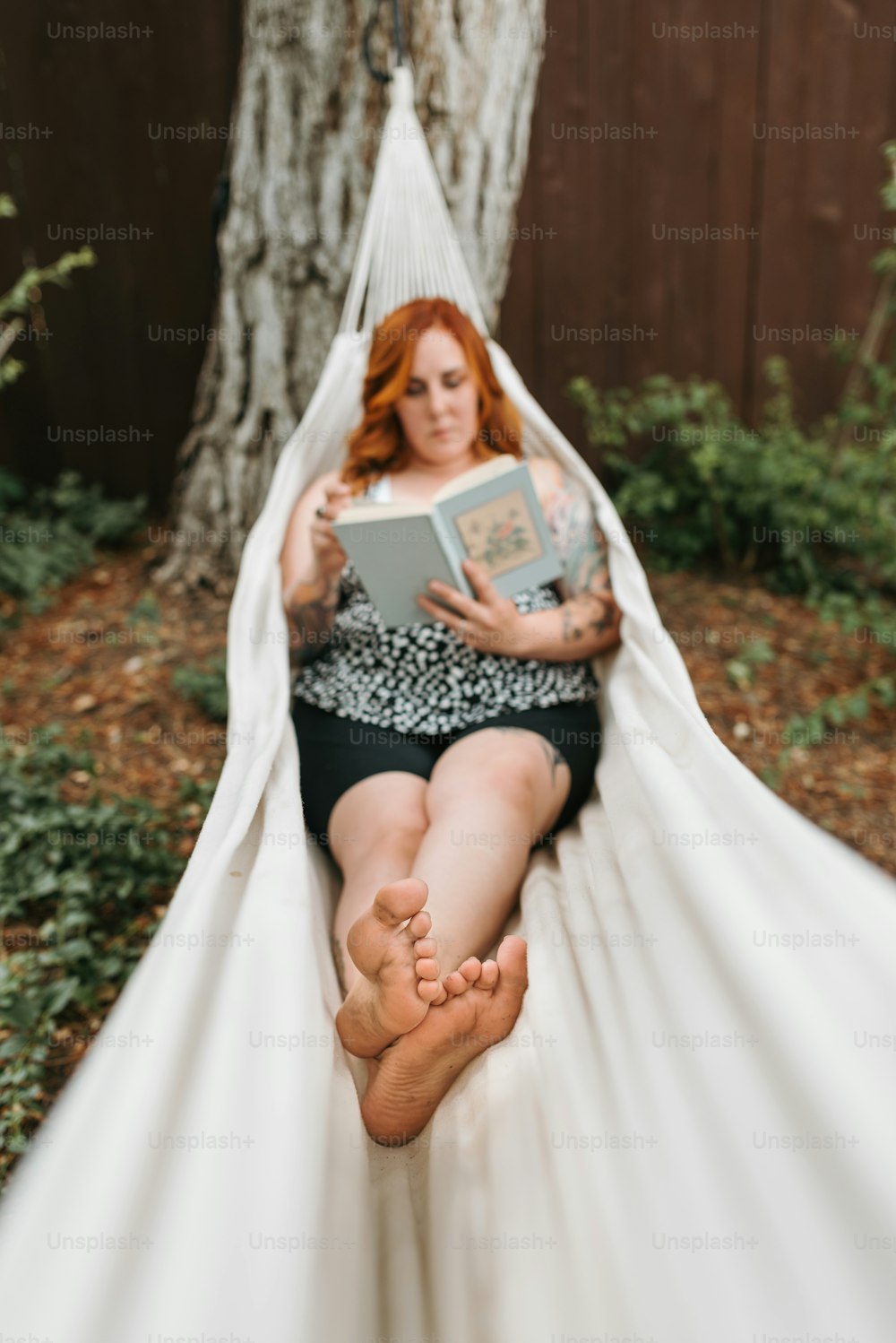 Una mujer sentada en una hamaca leyendo un libro