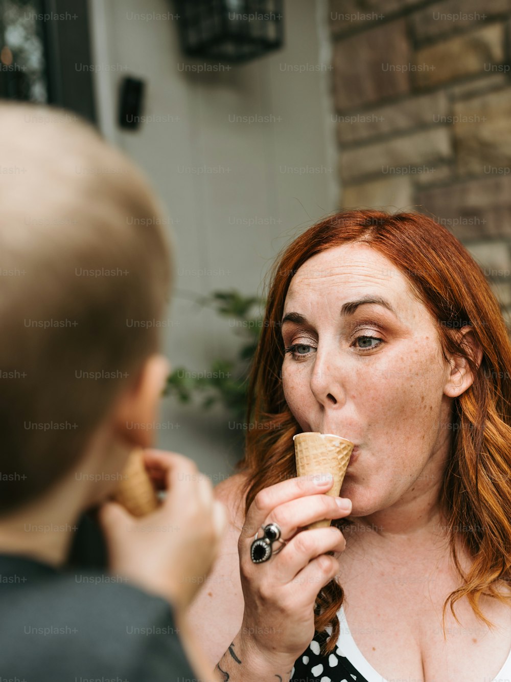 a woman eating an ice cream cone in front of a man