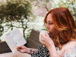 a woman drinking a cup of coffee and reading a book