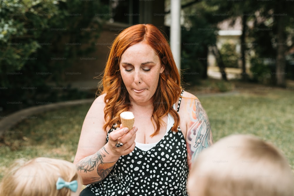 a woman with red hair holding a cupcake in her hands