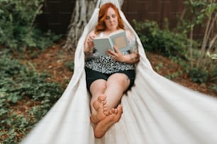 Una mujer sentada en una hamaca leyendo un libro