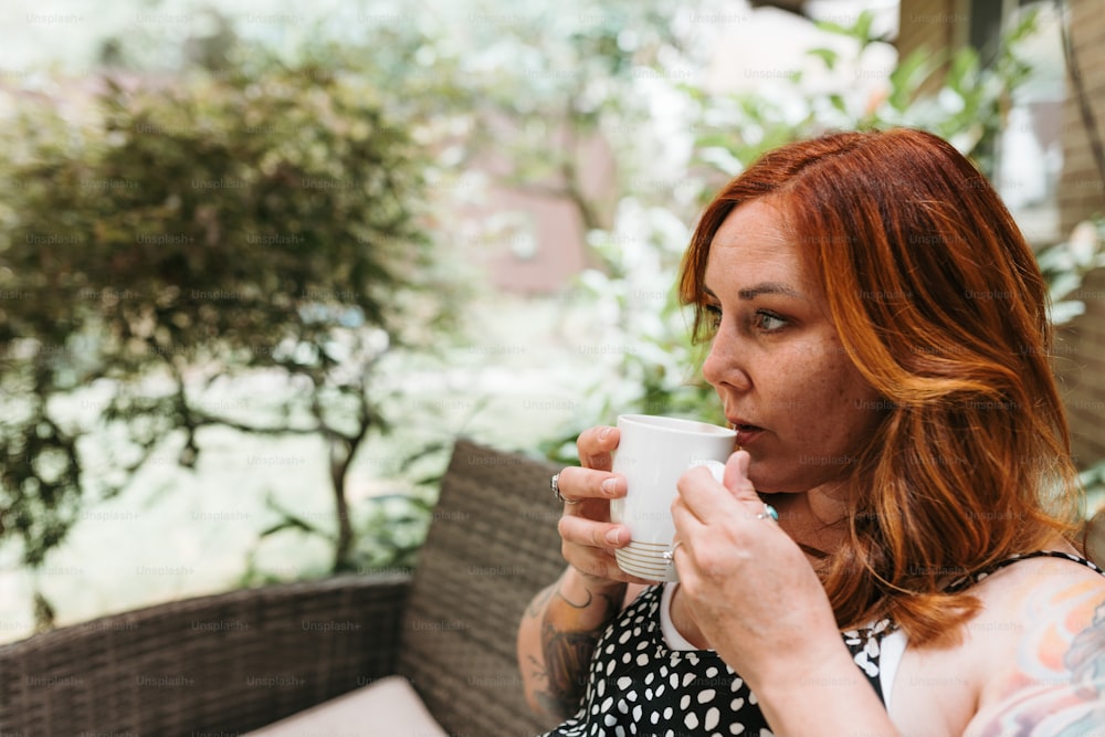 uma mulher com cabelos ruivos segurando uma xícara de café