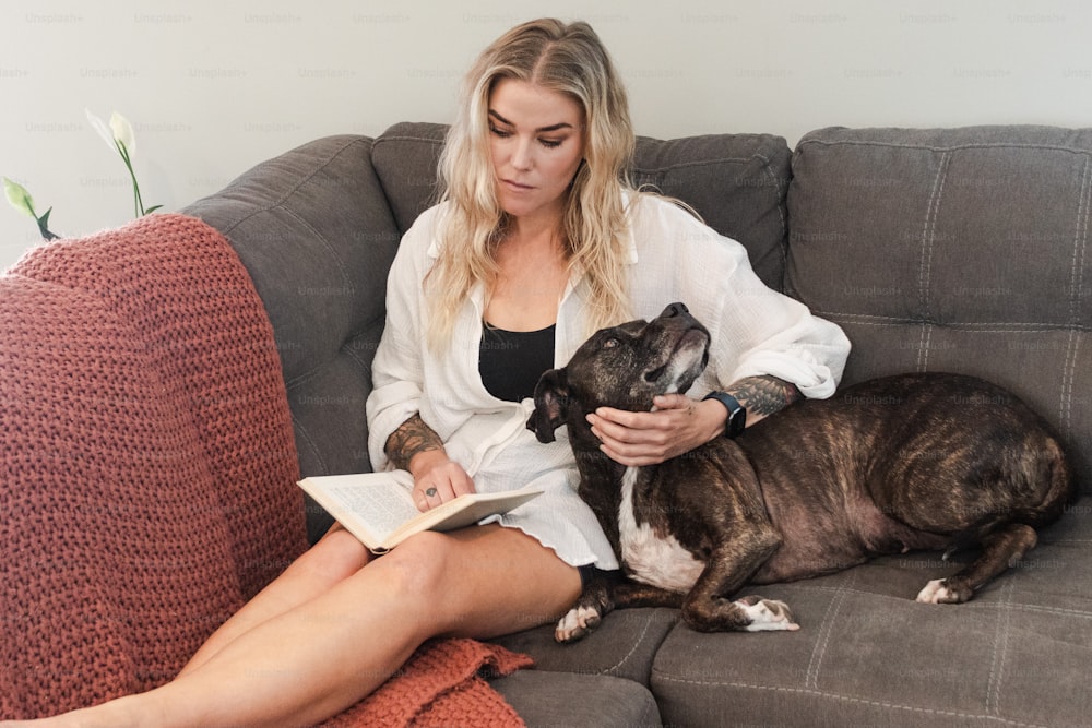 Una donna che si siede su un divano con un cane