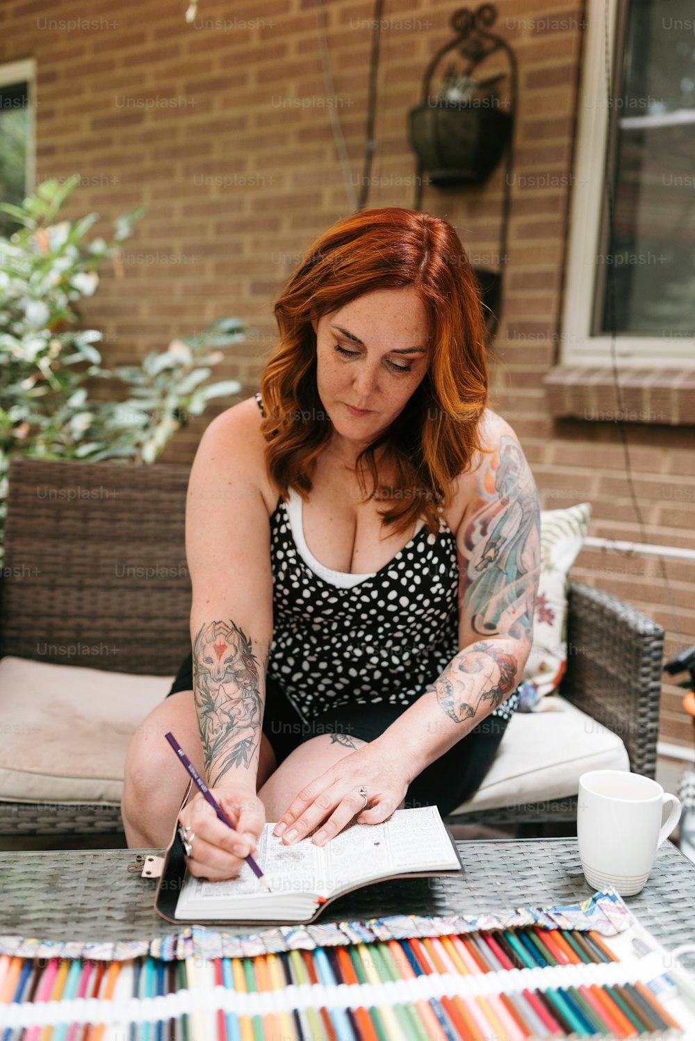 a woman sitting at a table writing on a piece of paper