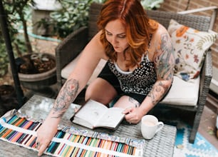 a woman sitting at a table with a book and a cup of coffee