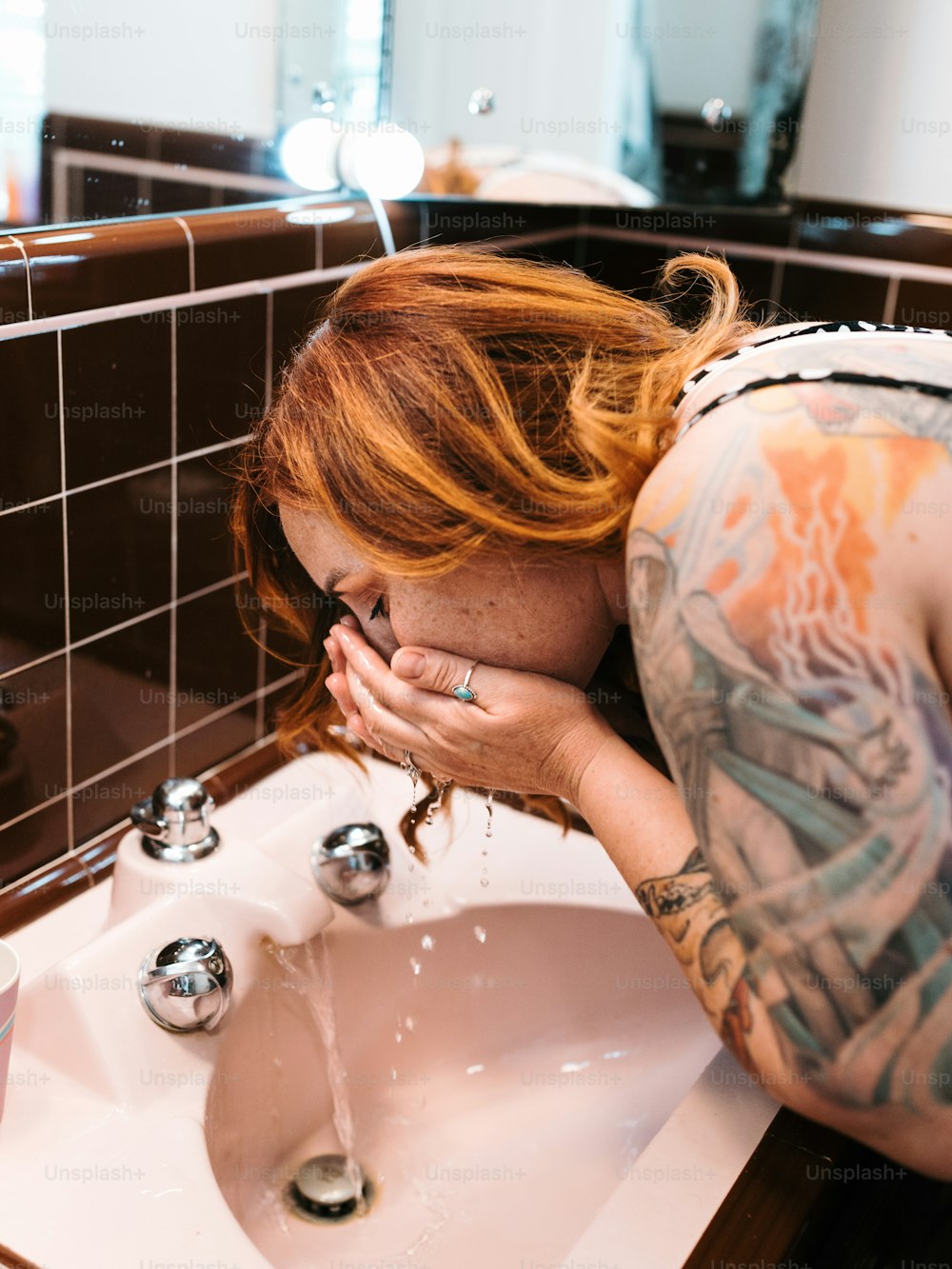 a woman with red hair is leaning over a sink