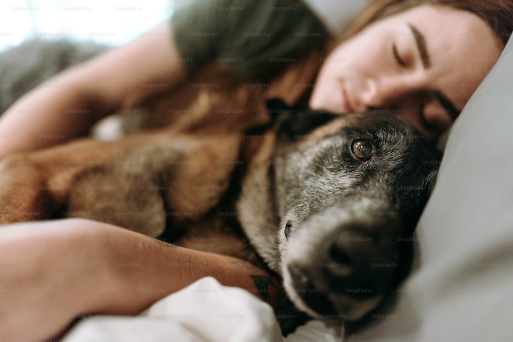 a woman laying in bed with her dog