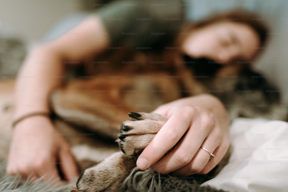 a woman laying on top of a bed with a cat