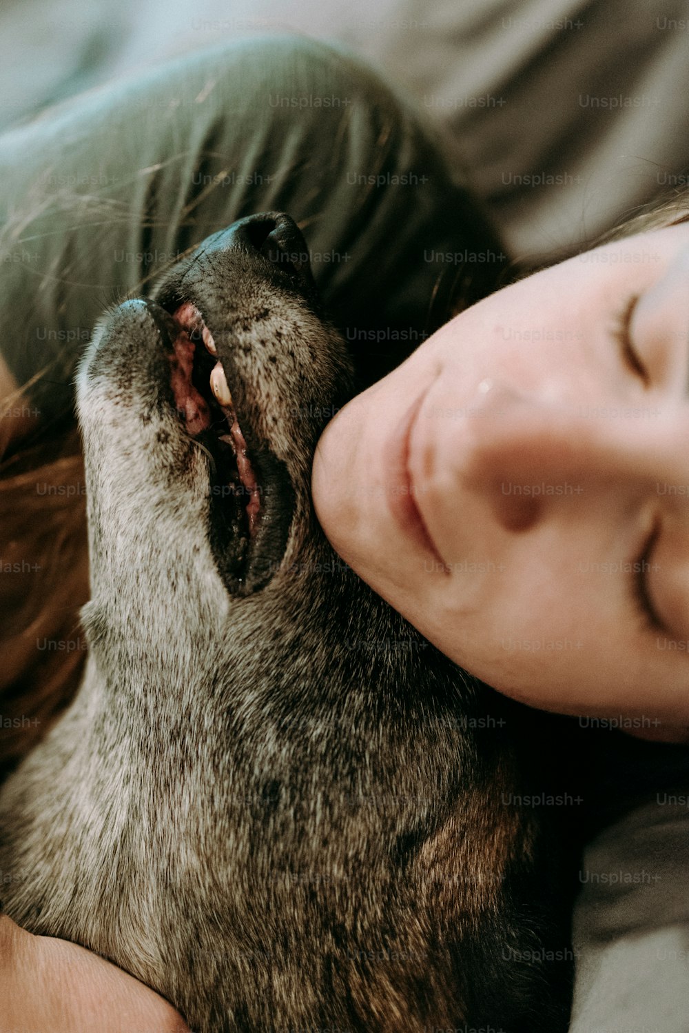 a woman laying on top of a bed next to a dog