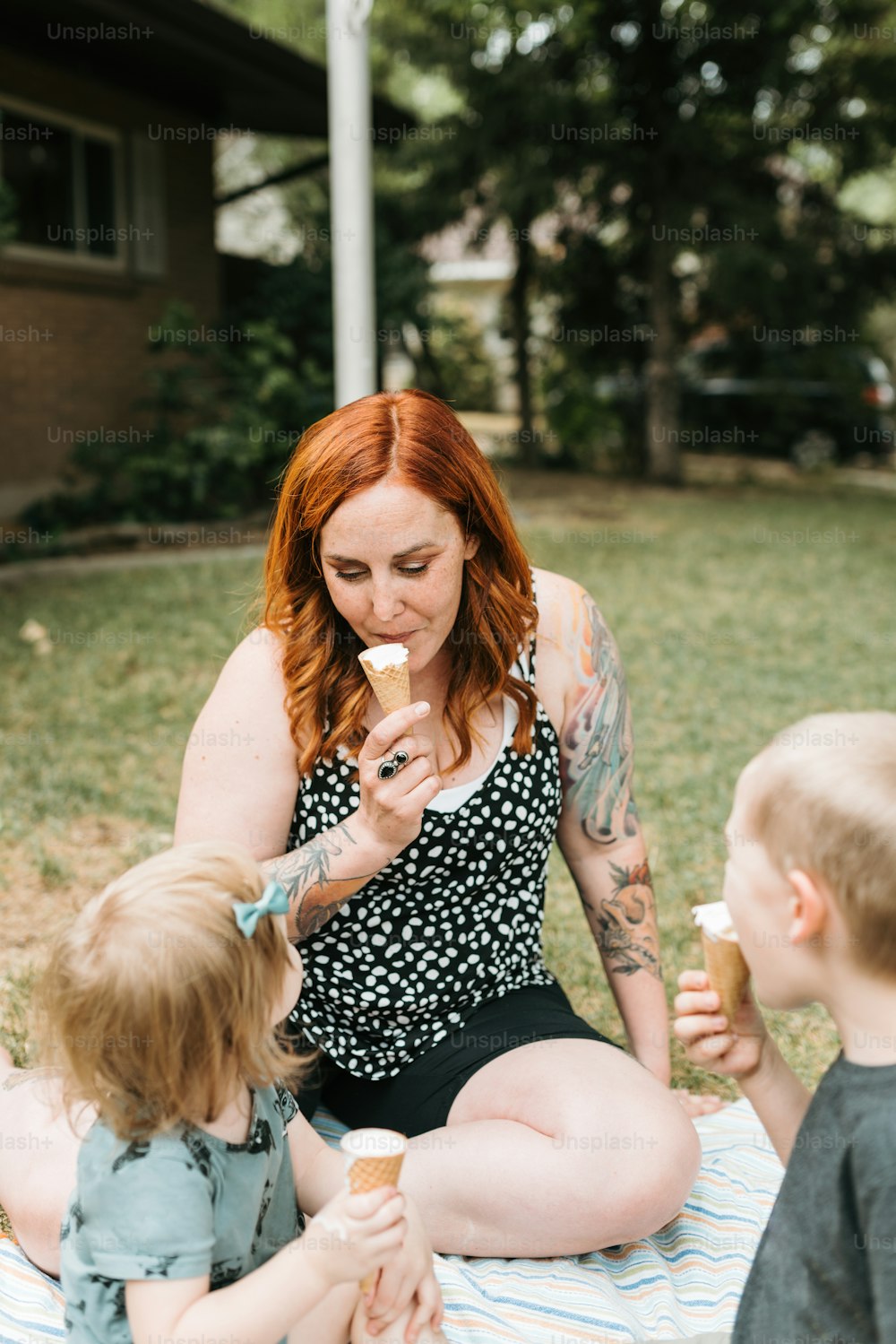 a woman sitting on a blanket eating ice cream