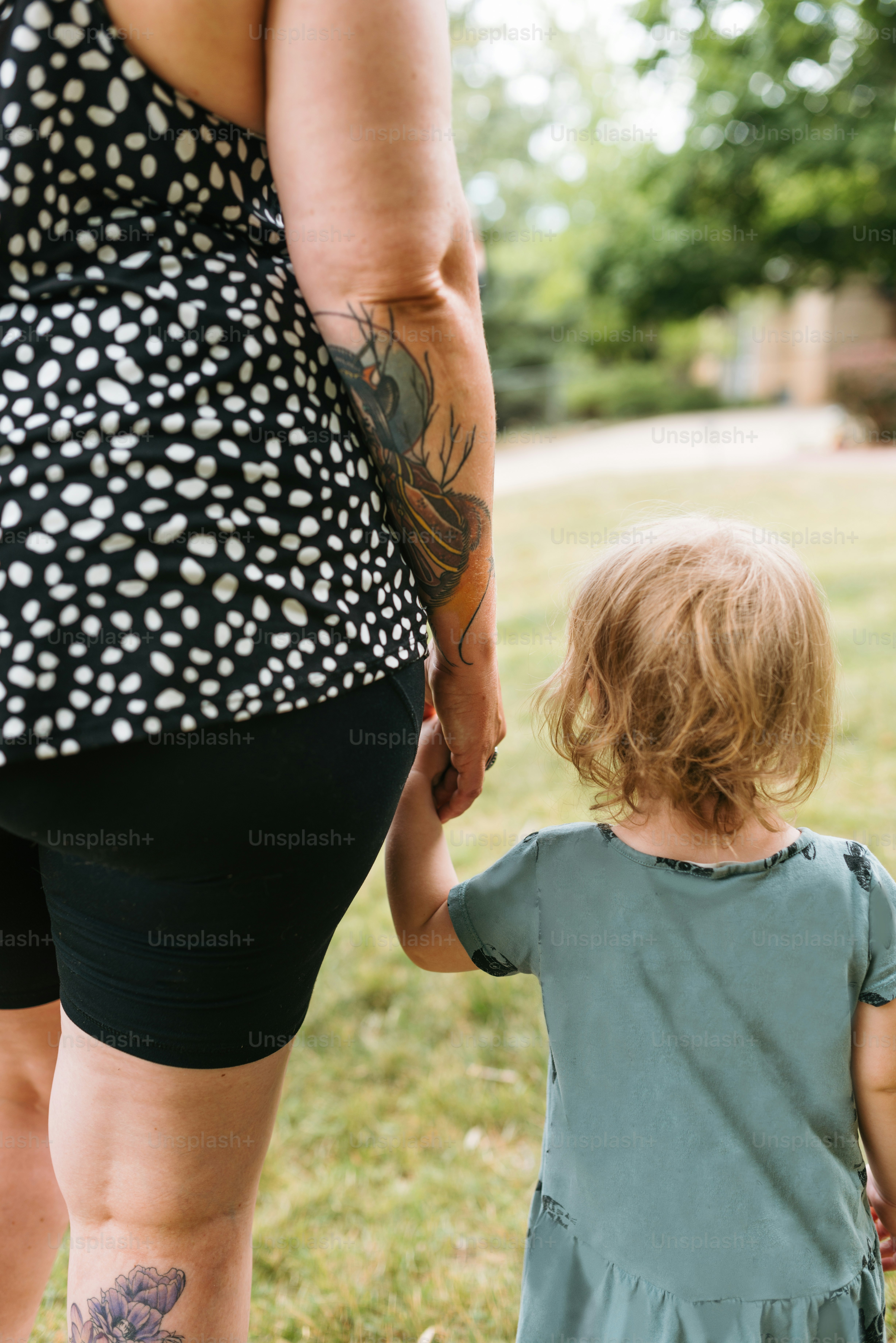 a woman holding the hand of a little girl