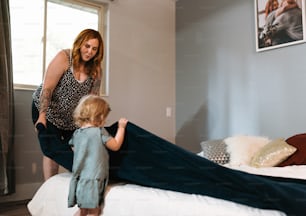 a woman standing next to a little girl on a bed