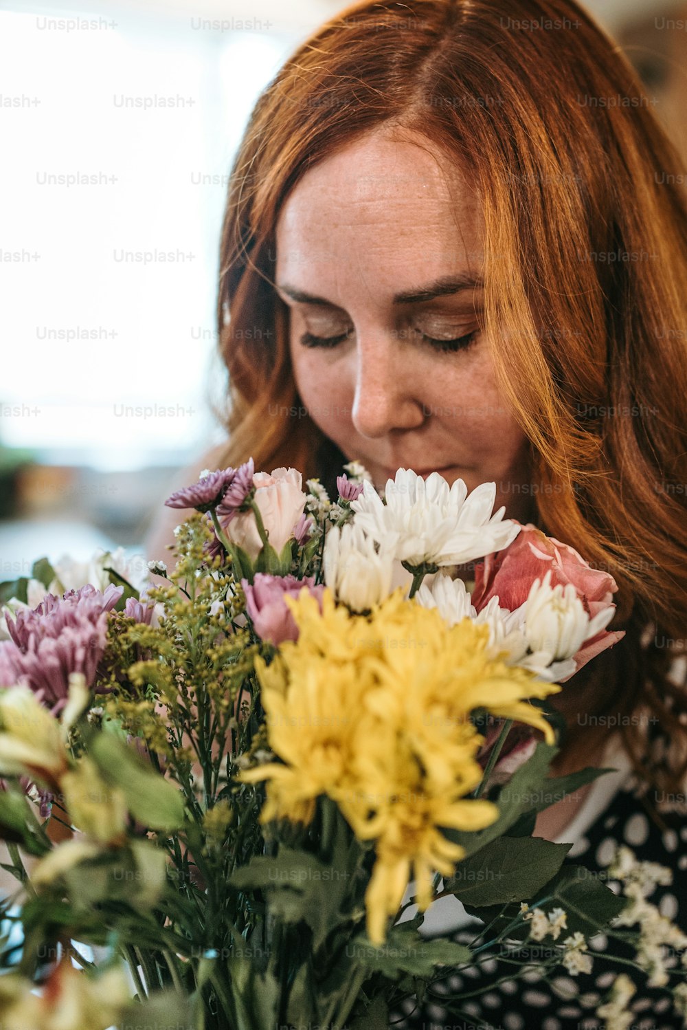 花瓶に花の束の匂いを嗅ぐ女性