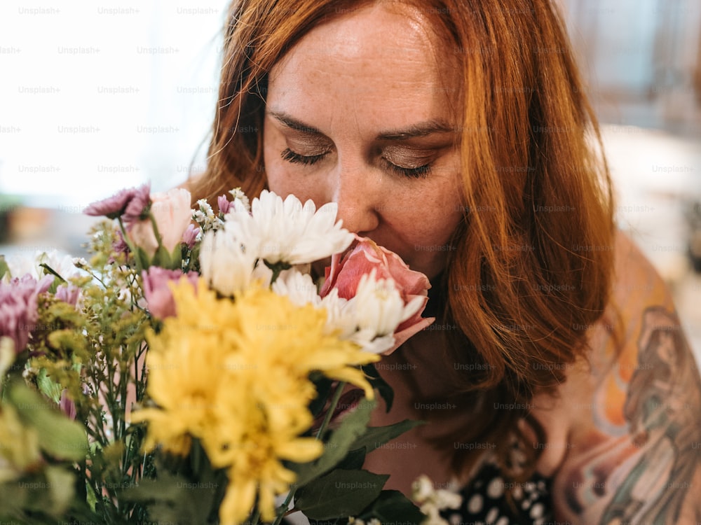 Une femme sentant un bouquet de fleurs les yeux fermés