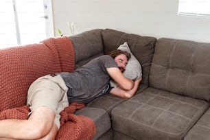 Un homme allongé sur un canapé avec sa tête sur un oreiller