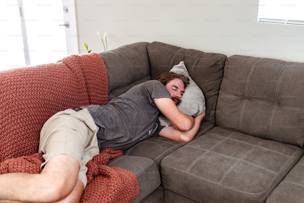 a man laying on a couch with his head on a pillow