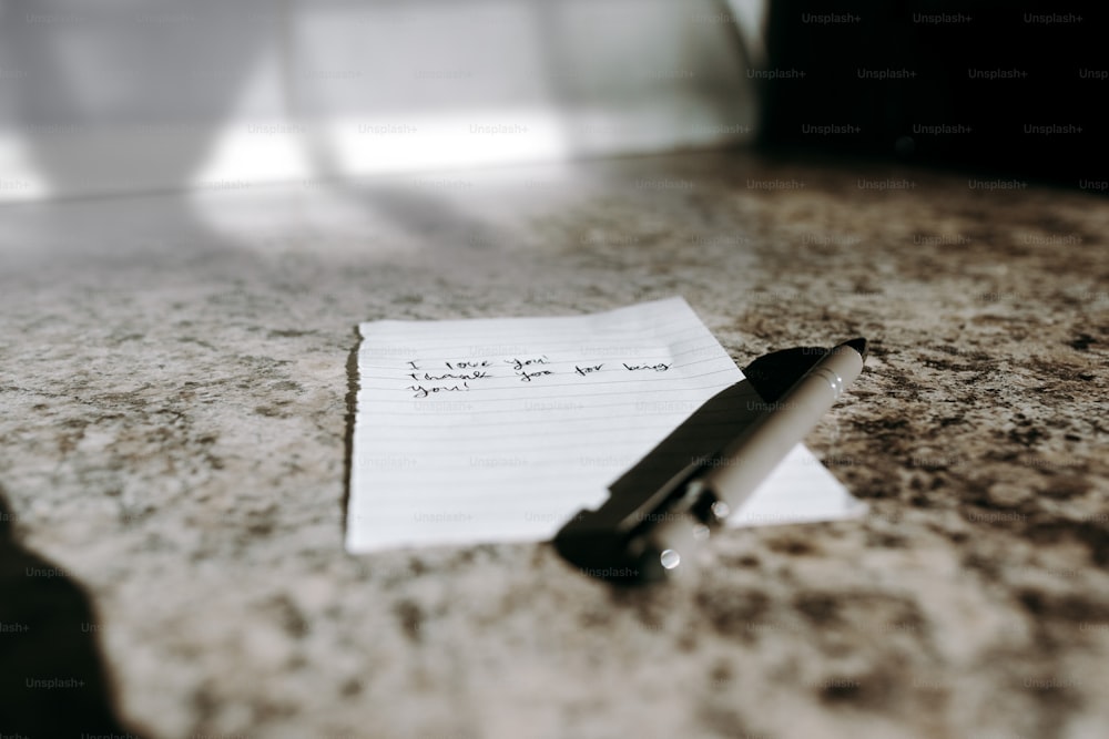uma nota sentada em cima de um balcão ao lado de uma caneta