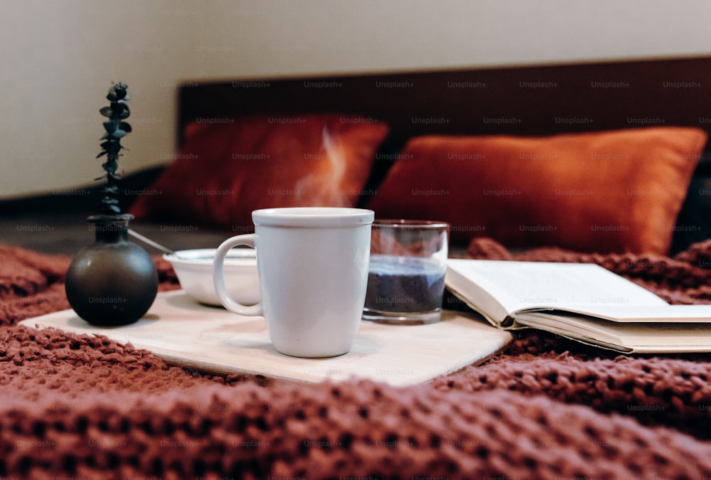 a cup of coffee and a book on a bed