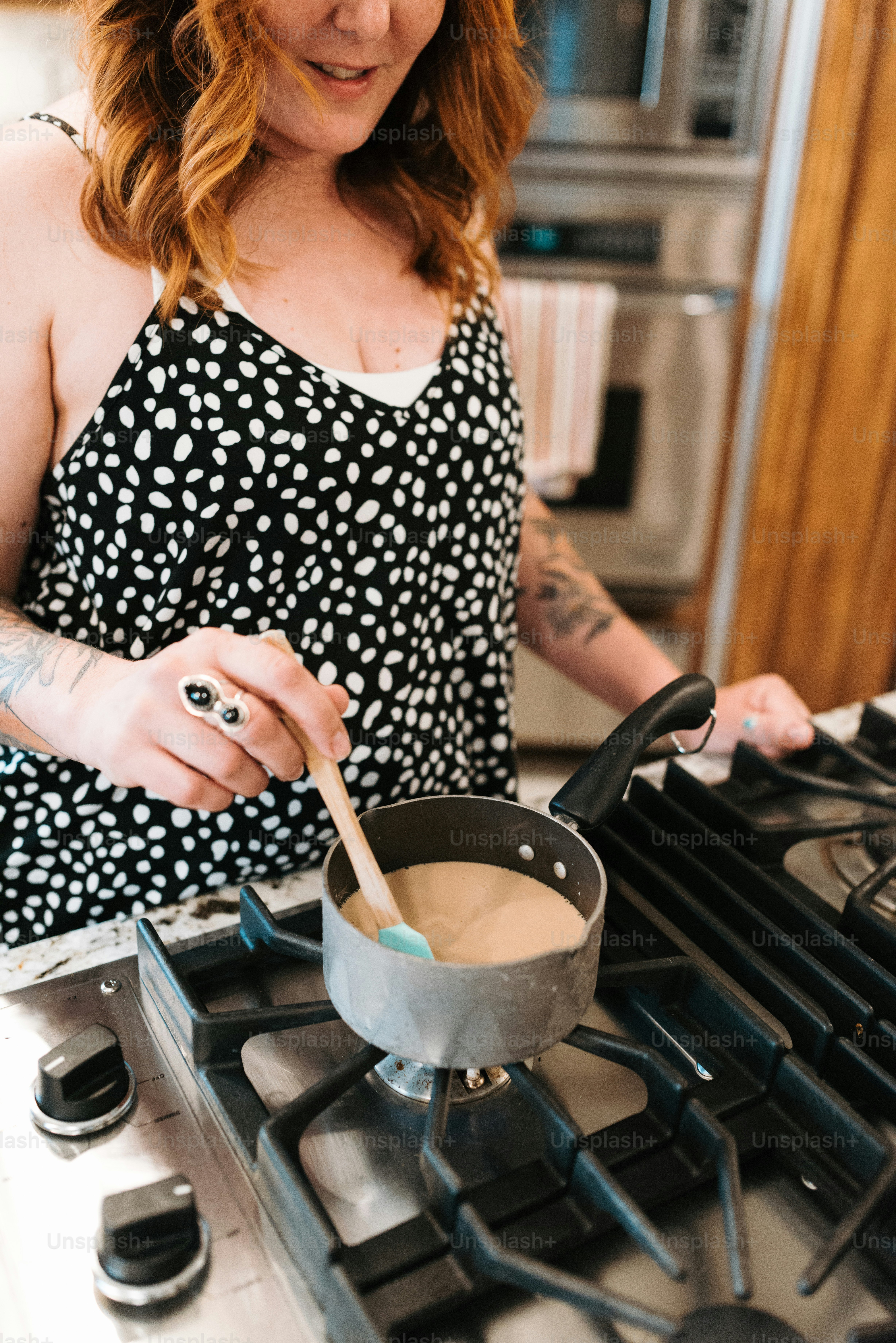 Une femme en robe noire et blanche remuant un pot de nourriture
