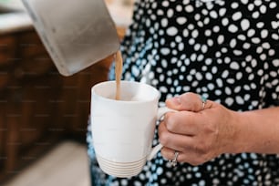 Una mujer vertiendo café en una taza blanca