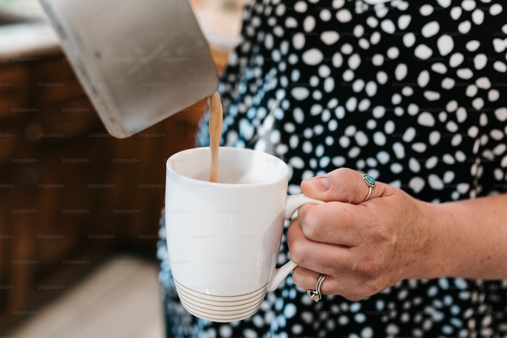 uma mulher derramando café em uma xícara branca