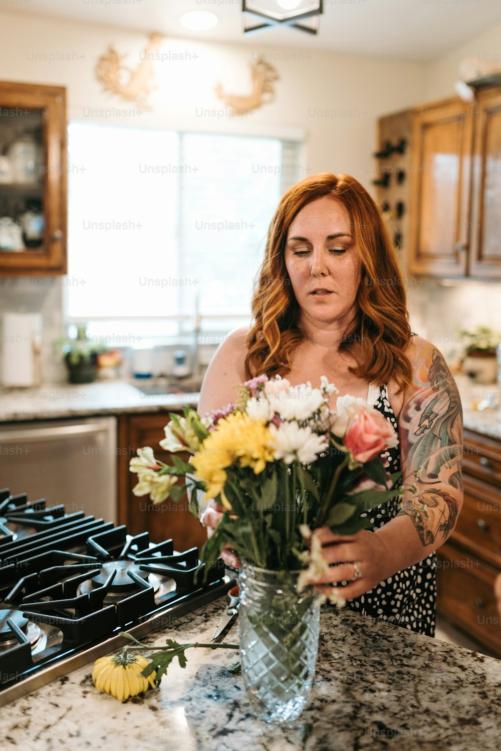 a woman standing in a kitchen holding a vase of flowers