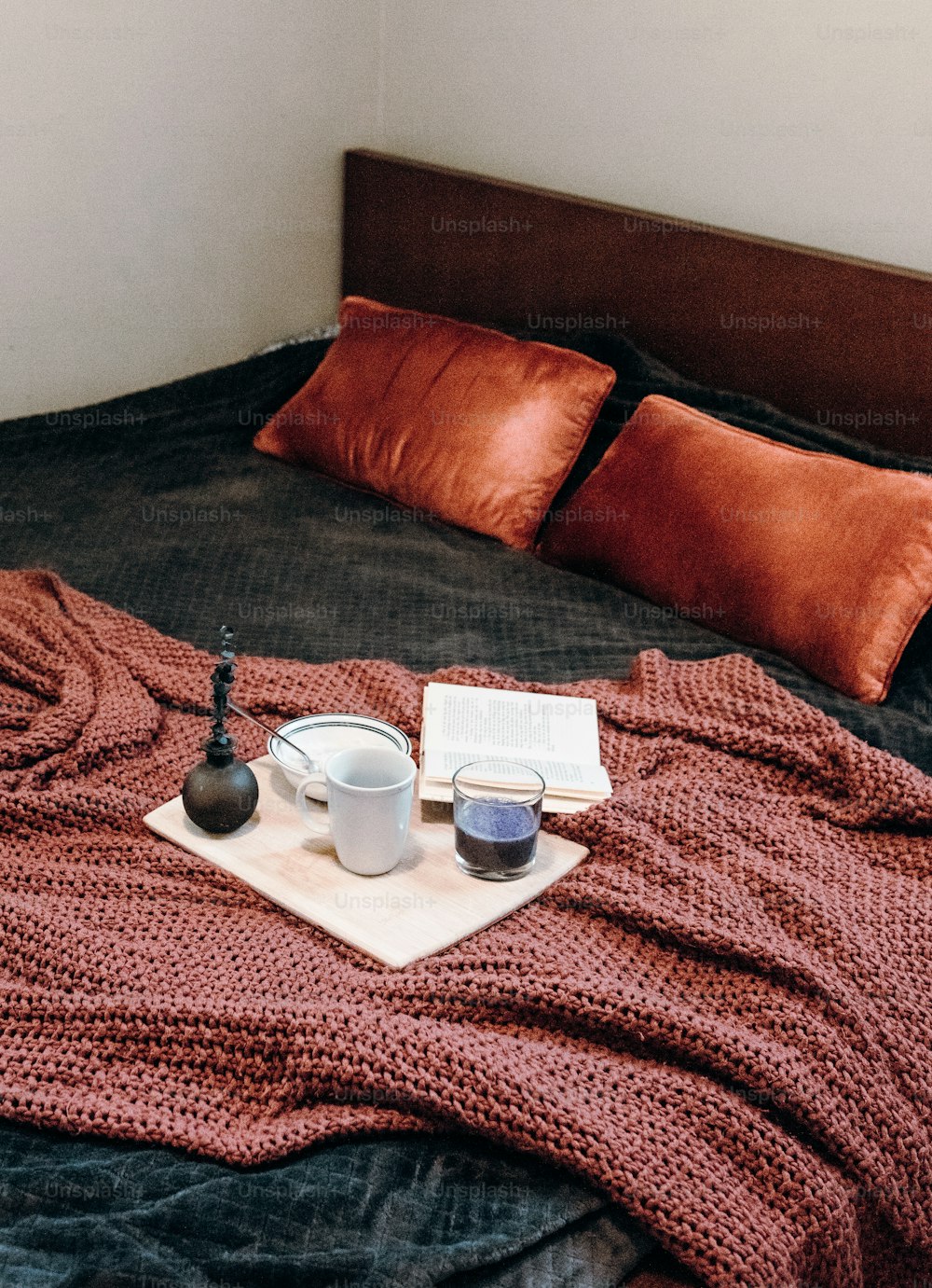 a bed with a book and two cups on it