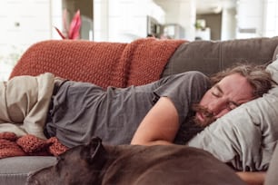 Un uomo sdraiato su un divano accanto a un cane