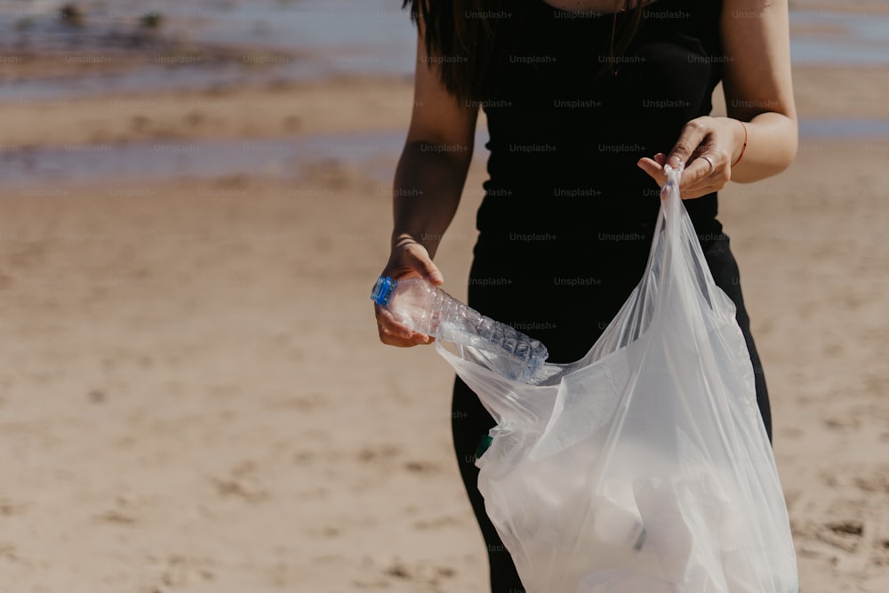 a woman holding a plastic bag on the beach