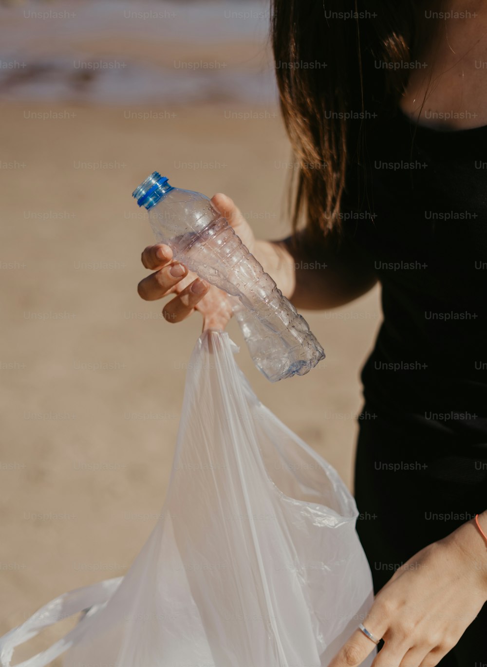 une femme tenant un sac en plastique et une bouteille d’eau